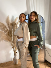 Load image into Gallery viewer, Two females modelling a cream tracksuit and a khaki tracksuit in a studio
