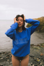 Load image into Gallery viewer, Female modelling blue signature sweatshirt on a beach
