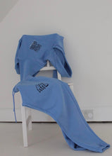 Load image into Gallery viewer, Blue see you soon tracksuit lying across a white chair
