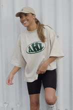Load image into Gallery viewer, Female model wearing AHL Apparel Natural Raw oversized T-shirt with green AHL logo
