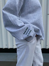 Load image into Gallery viewer, Model wearing grey AHL Apparel sweatshirt with Made With Care sleeve print

