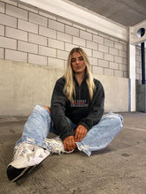 Load image into Gallery viewer, Female sitting on floor of a carpark wearing grey fleece
