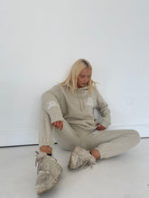 Load image into Gallery viewer, Female sitting on floor wearing cream tracksuit
