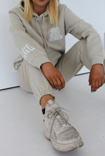 Load image into Gallery viewer, Female sitting on floor modelling she just shines cream tracksuit
